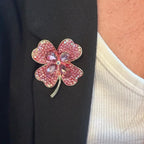 Jakris four-leaf clover brooch featuring pink crystals pinned to a black blazer lapel