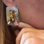 Jakris rectangular silver earring featuring gold-toned beaded chains and central spheres worn on an earlobe