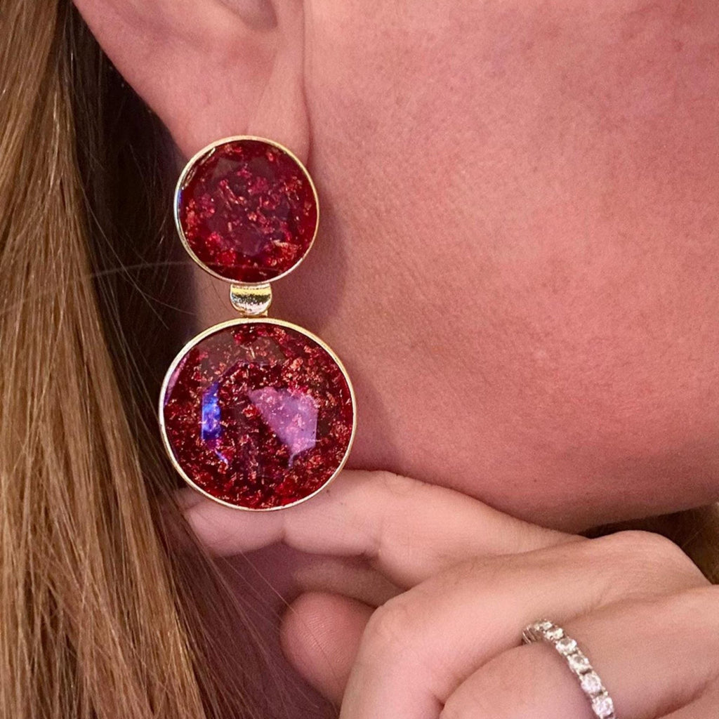 Jakris red crystal dangle earrings with gold-toned circular frames worn on a model