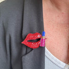 Jakris red lip and lipstick brooch featuring sparkling crystals pinned on a black blazer