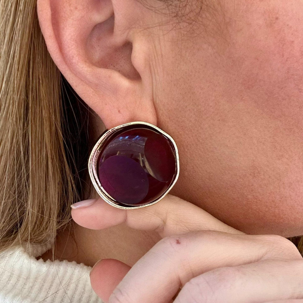 Jakris retro style large round earring with a deep red stone set in a gold-toned metal frame worn on an ear