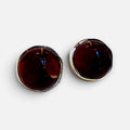 Jakris retro style earrings featuring large round deep red stones set in gold-toned metal on a marble surface.