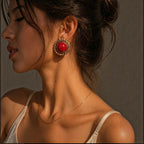 Jakris red sun-shaped stud earring with a gold scalloped frame worn by a woman in profile