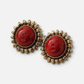 Jakris red sun earrings featuring a polished red cabochon center surrounded by a gold-toned sunburst petal frame.