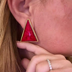 Jakris modern triangle earring with a vibrant red stone and gold-toned frame worn on an earlobe
