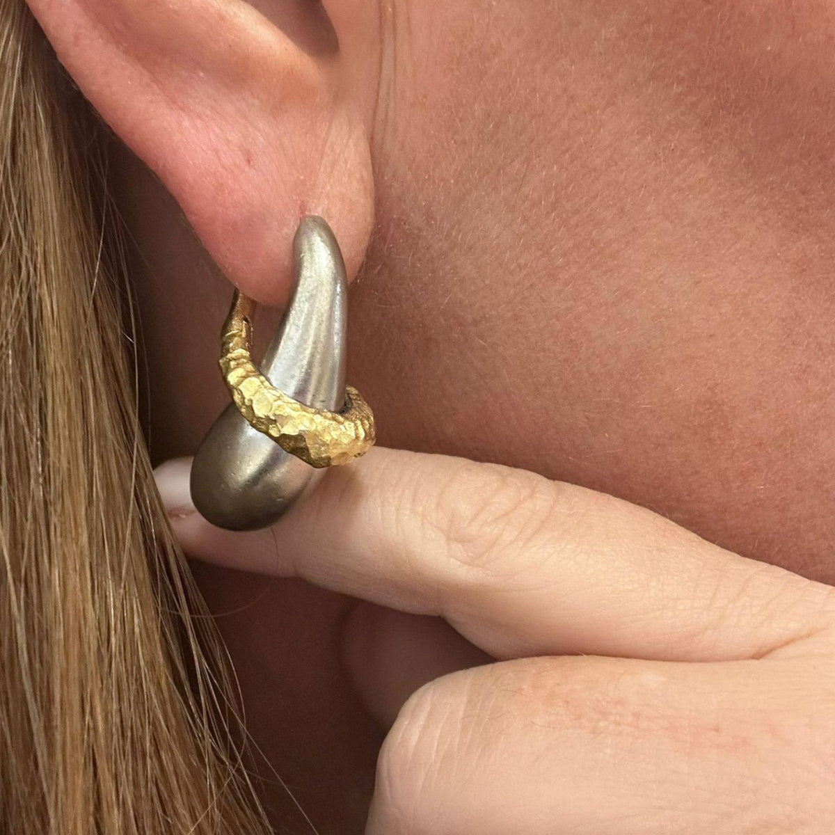 Jakris handmade sculptural hoop earring featuring a smooth silver-tone drop and a textured gold-plated accent