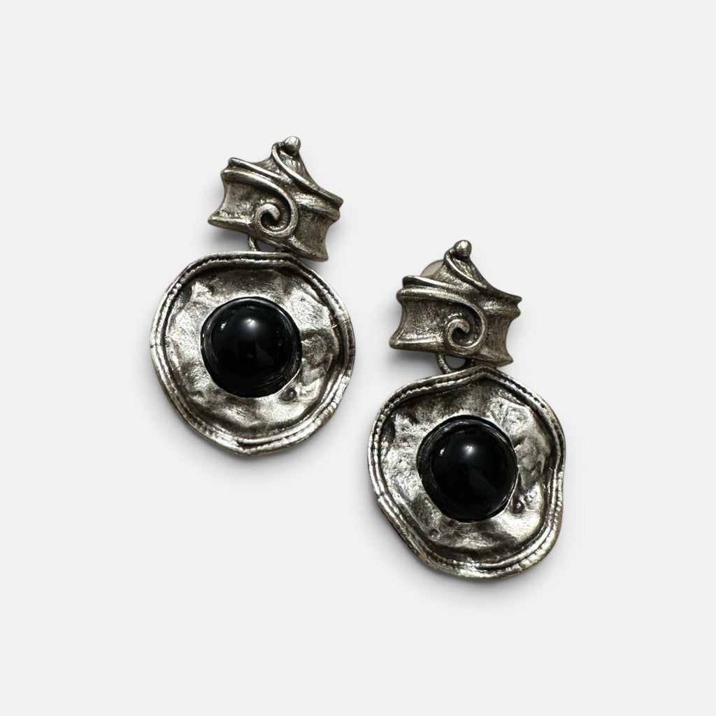 Jakris silver dangle earrings featuring a textured antique finish and a central black stone on a white surface.