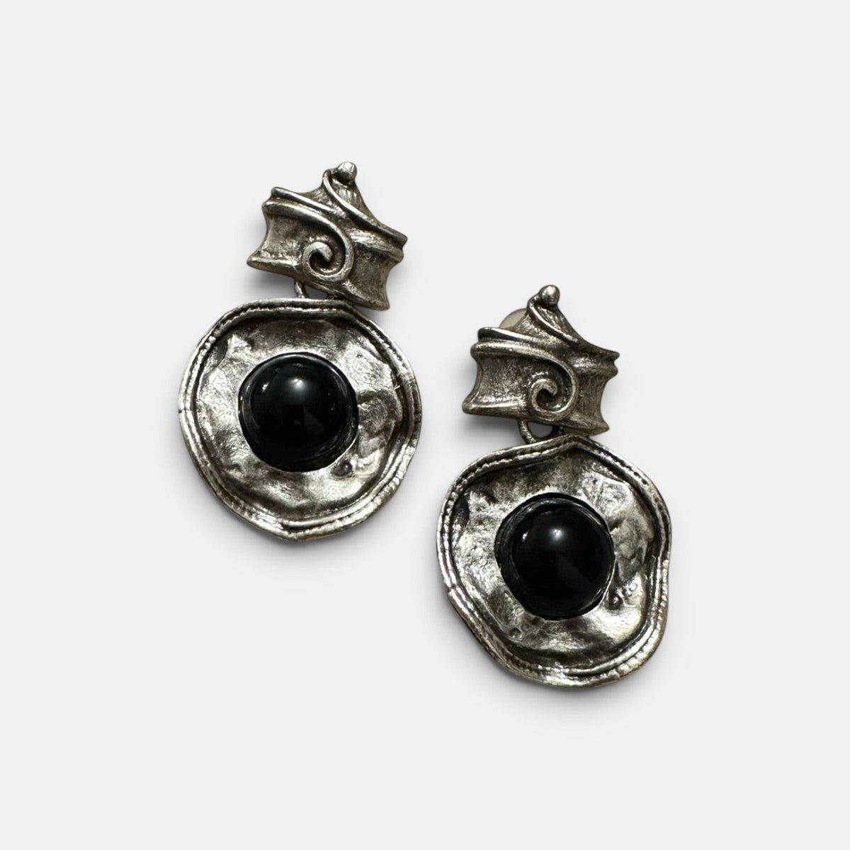 Jakris silver dangle earrings featuring a textured antique finish and a central black stone on a white surface.