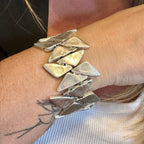 Jakris chunky silver-tone geometric elastic bracelet worn on a wrist with triangular metal links.