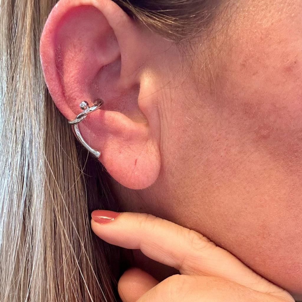 Jakris minimalist silver knot cartilage earring worn on the ear, featuring a delicate knotted design.