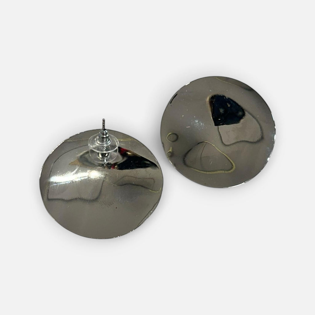 Jakris silver-toned circular mirror earrings with a polished reflective finish on a white fabric background