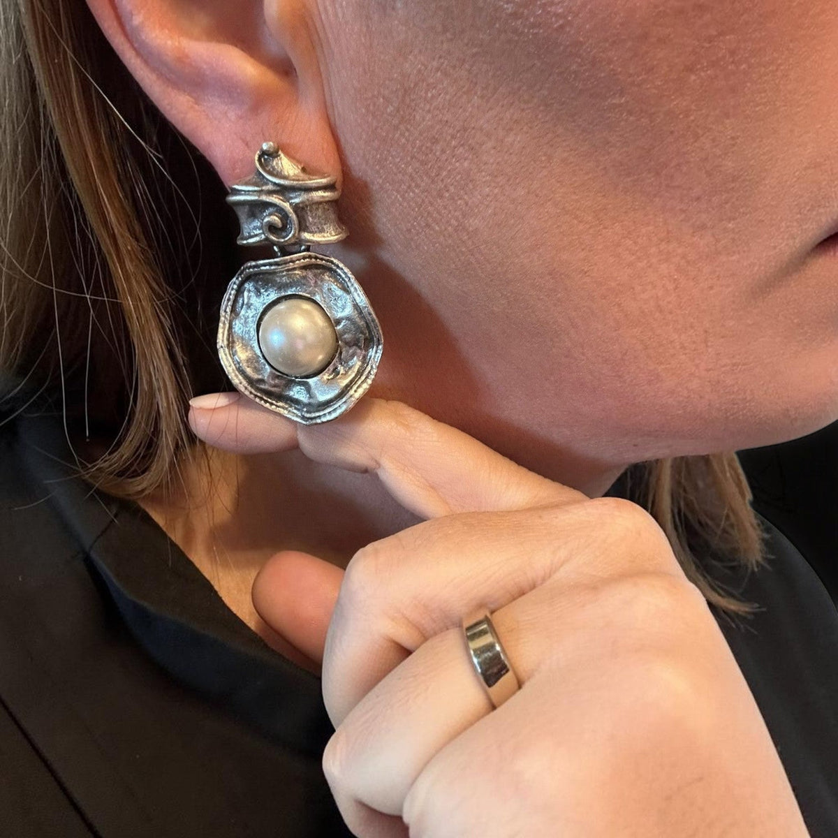 Jakris silver-tone statement earring featuring a central pearl and textured metal design worn on an earlobe.
