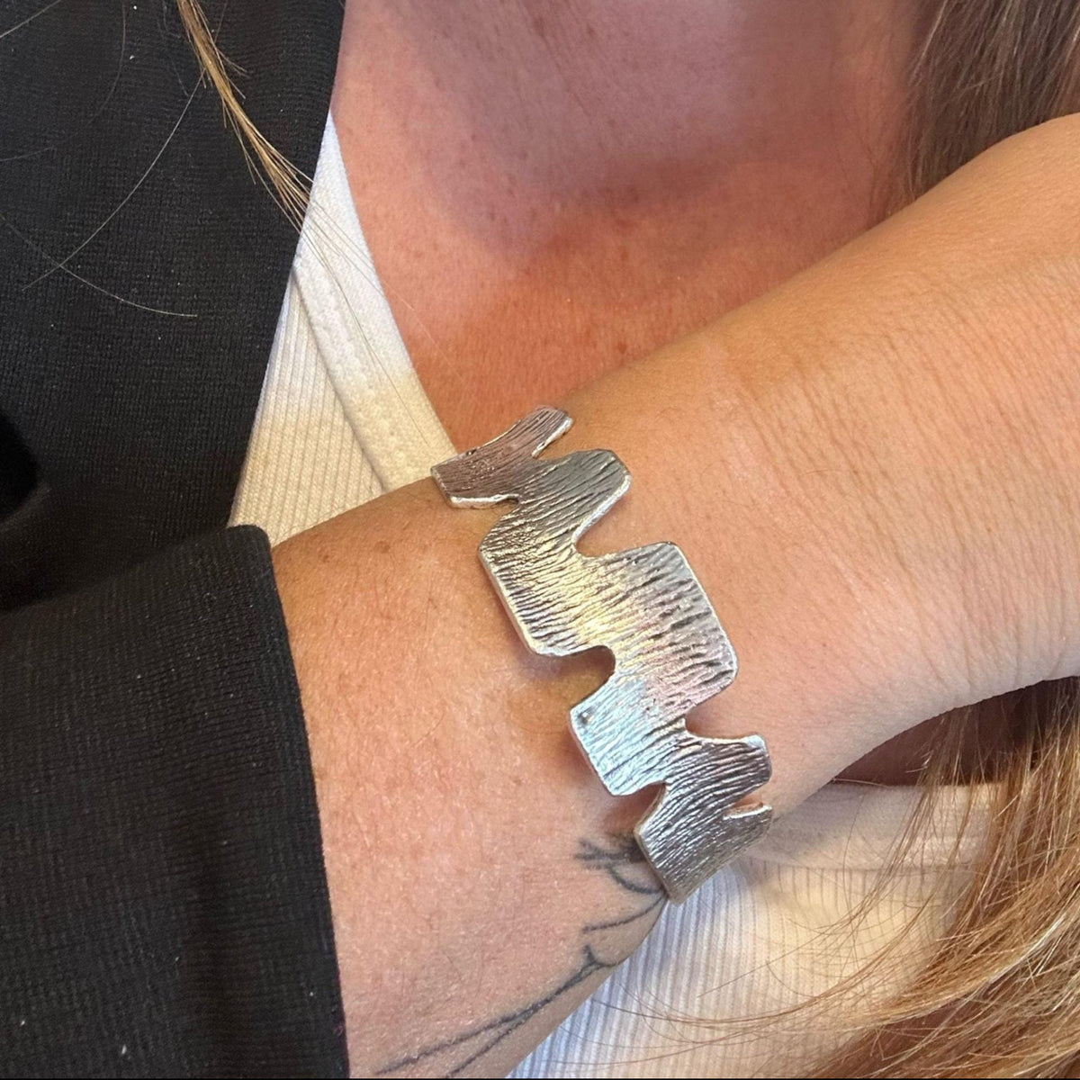 Jakris handmade silver-plated cuff bracelet featuring a textured zig-zag pattern worn on a wrist