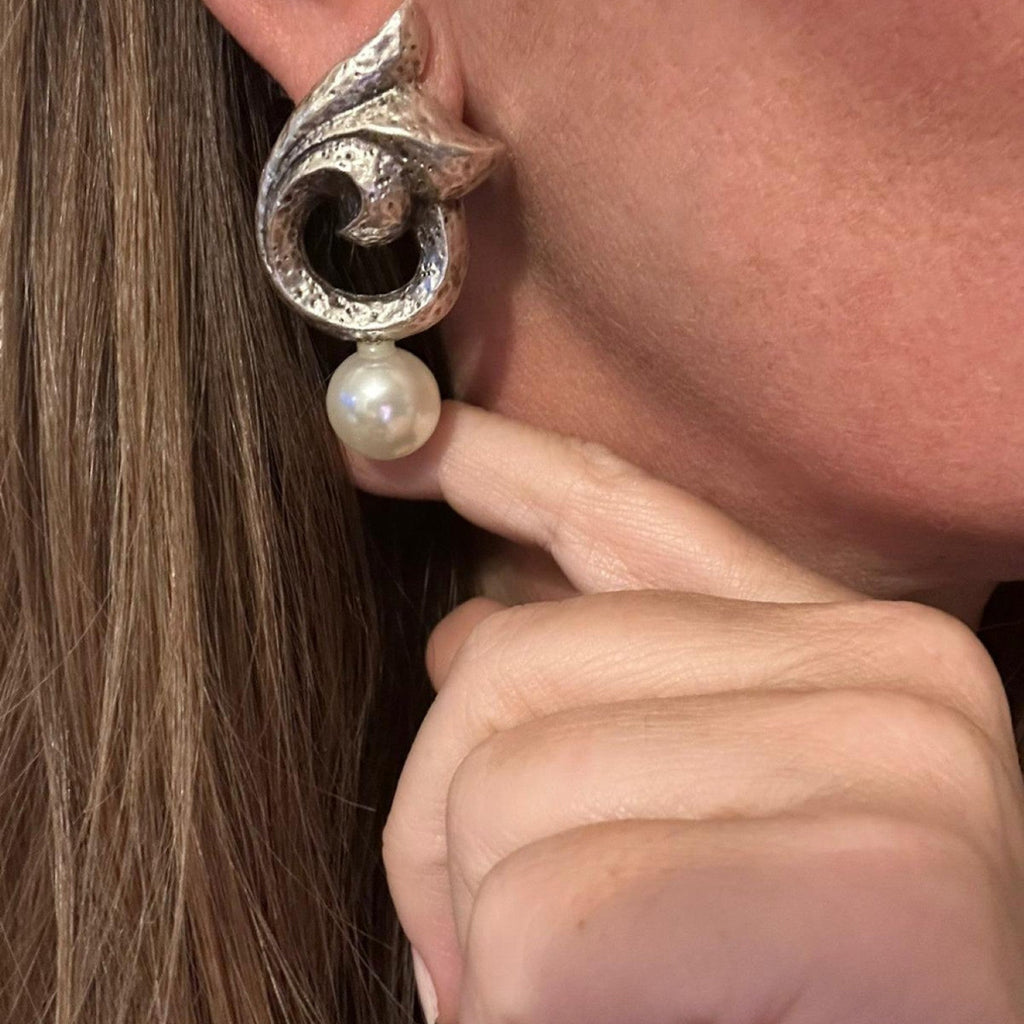 Jakris silver-plated statement earrings with a sculptural textured design and a dangling faux pearl on a model