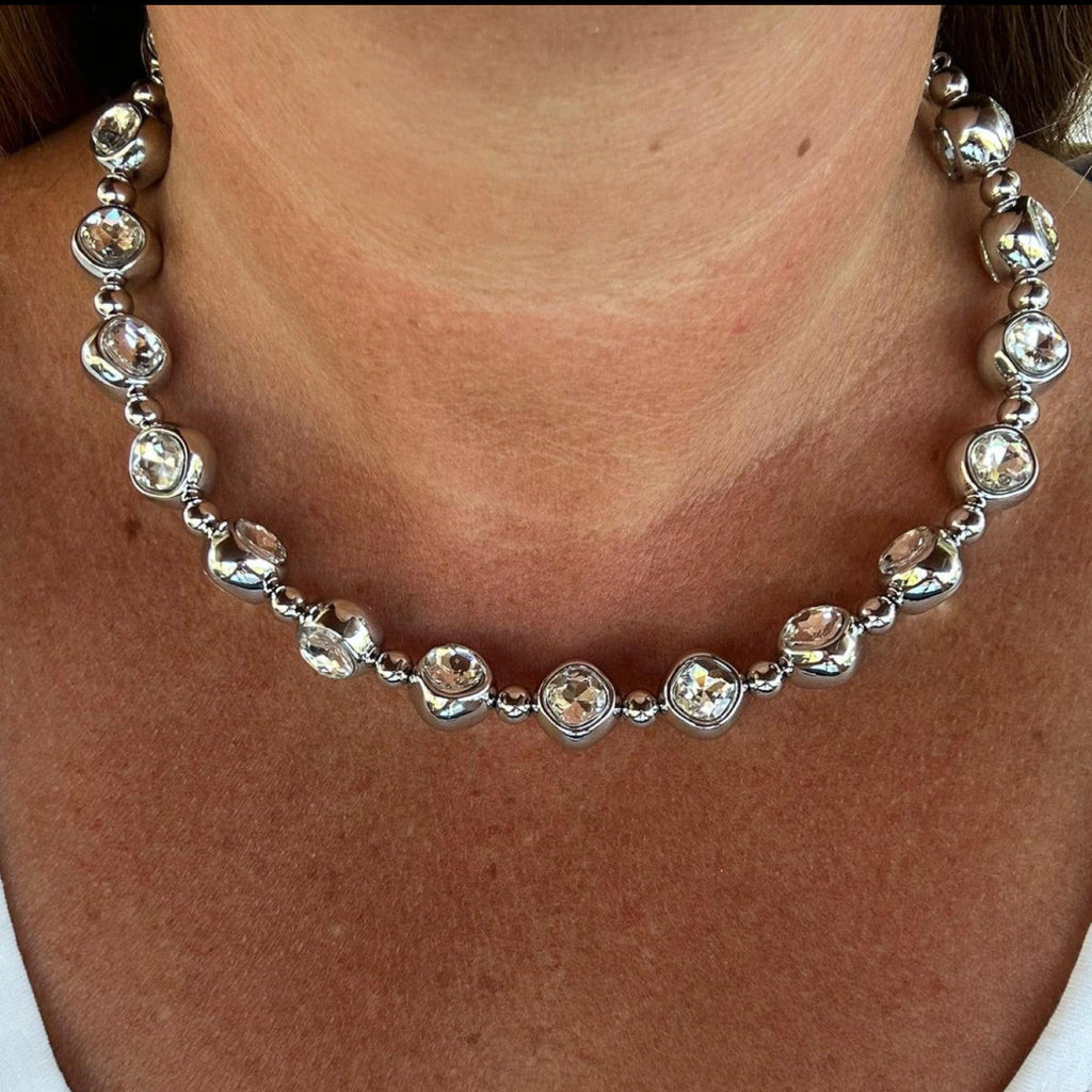 Jakris silver tone choker necklace featuring large clear faceted stones and polished metal beads worn on a neck