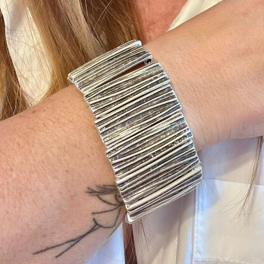 Jakris silver-toned textured wide elastic cuff bracelet worn on a wrist