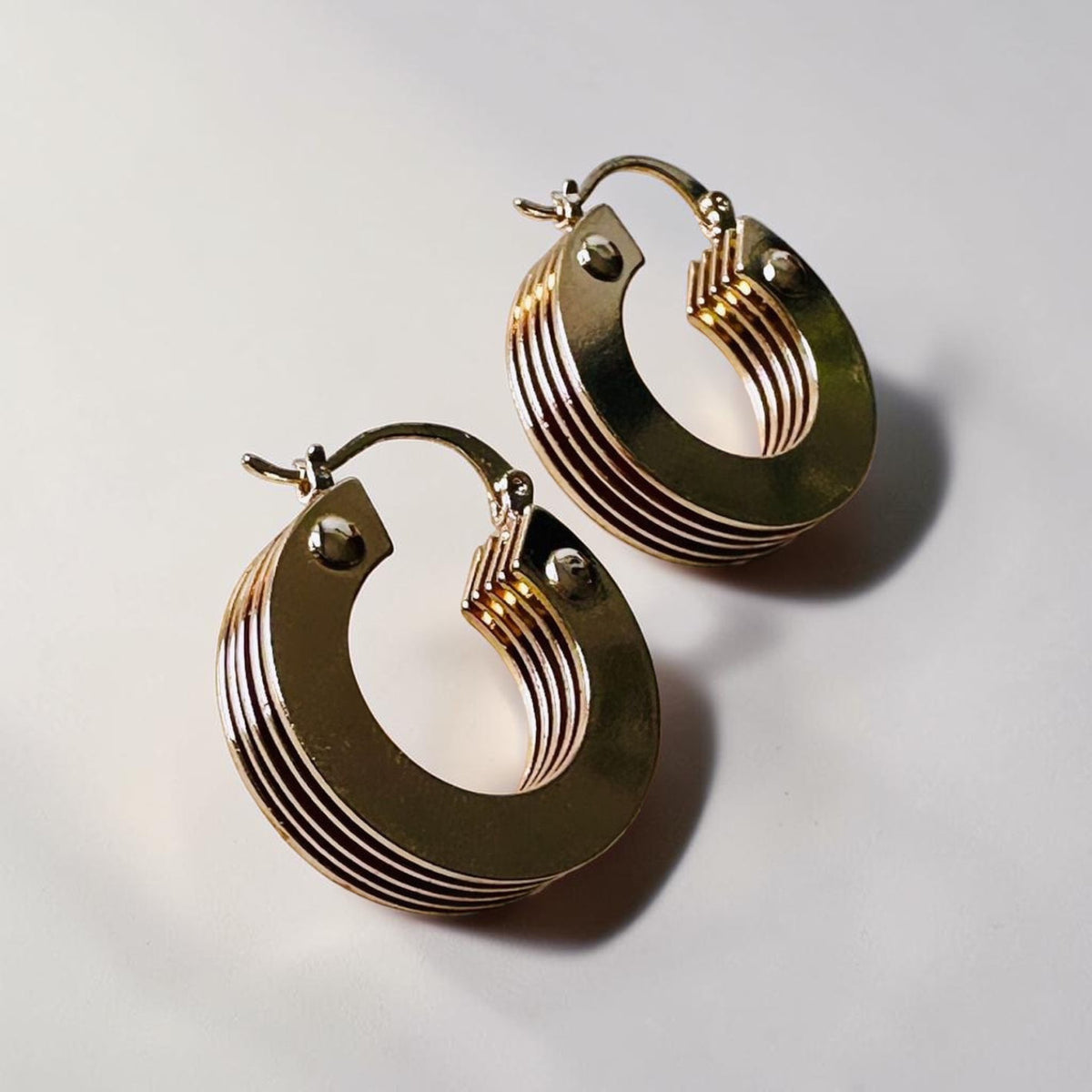 Jakris small gold hoop earrings featuring a layered 5-tier thick design with a polished metallic finish.
