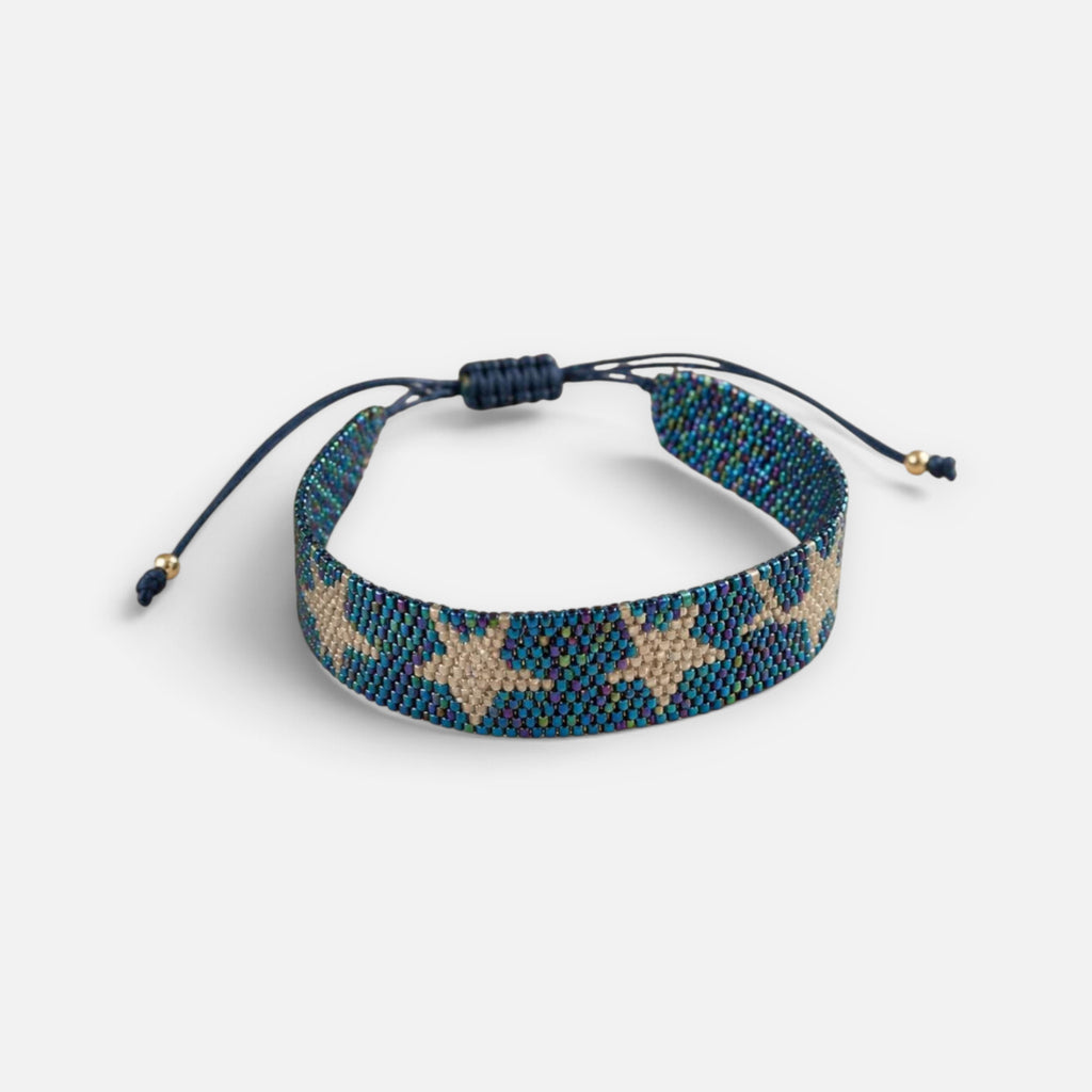 Jakris woven beaded bracelet featuring a star pattern in iridescent blue and metallic gold beads with adjustable cord
