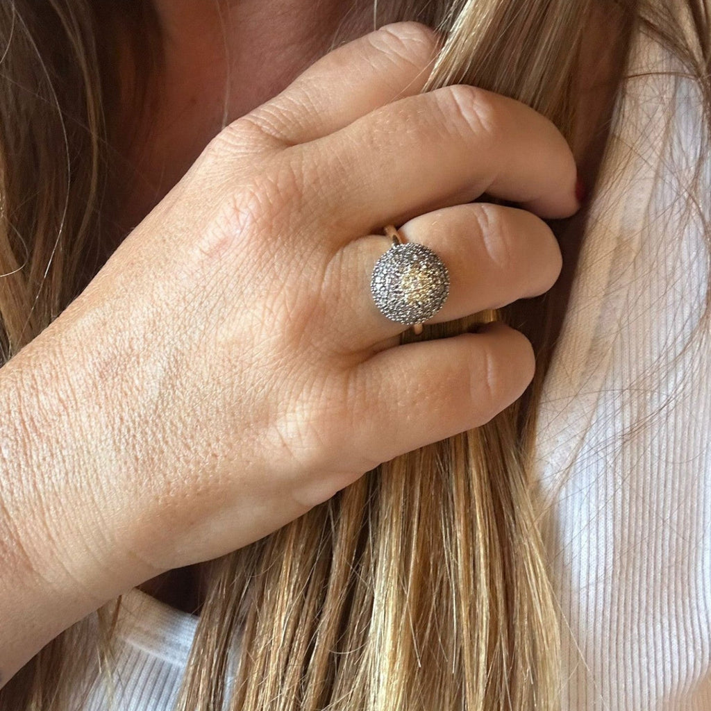 Jakris gold ring featuring a large, round, star-patterned zircon stone setting worn on a woman's finger.
