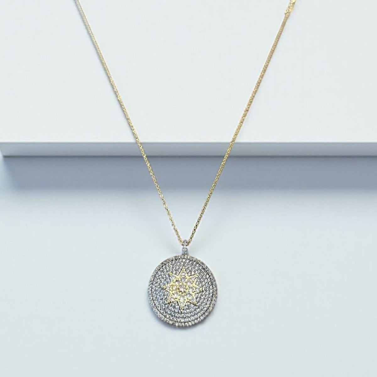 Jakris round pendant necklace featuring a central star motif encrusted with sparkling white and yellow zircon stones.