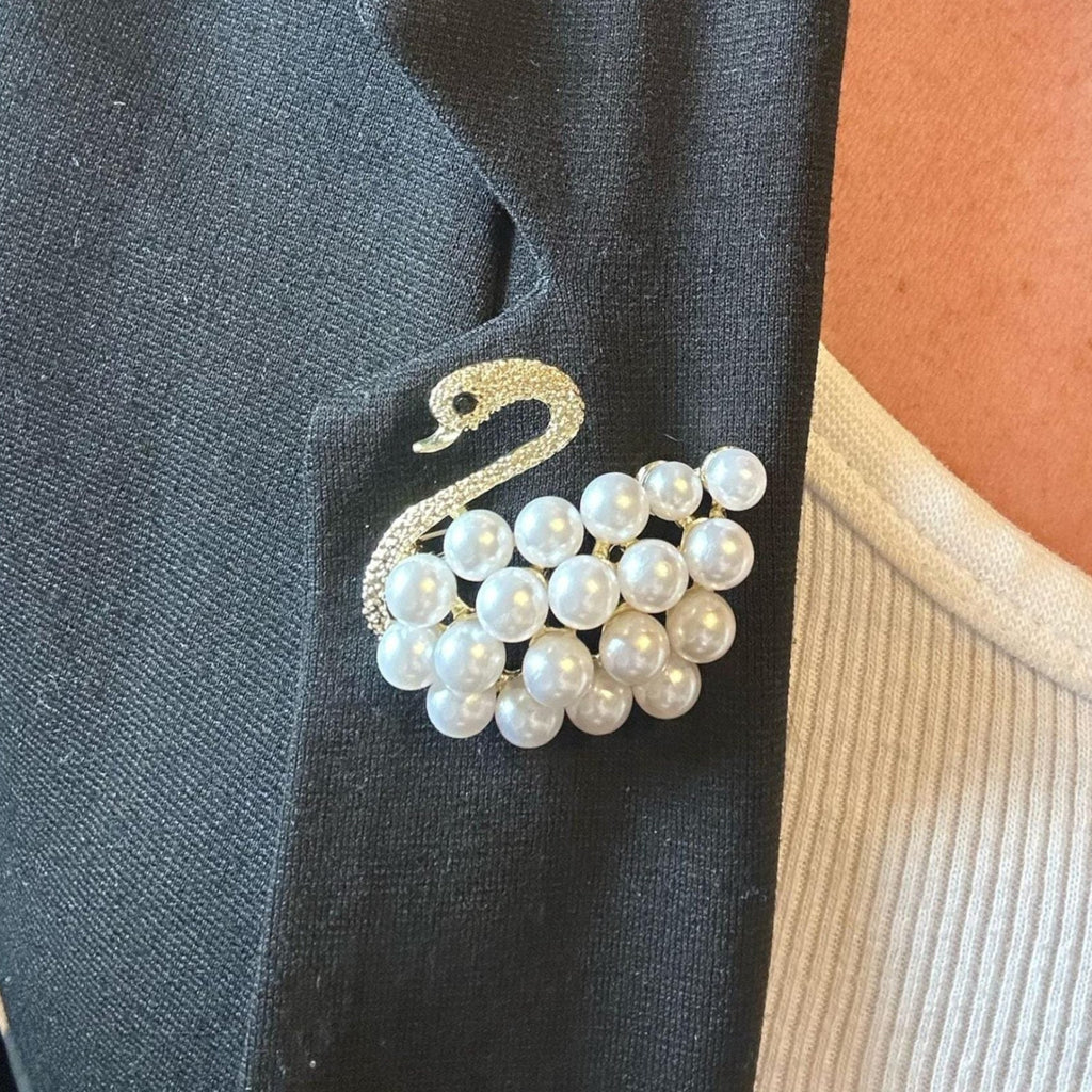 Jakris vintage-inspired swan brooch featuring white pearls and sparkling crystals pinned to a black blazer