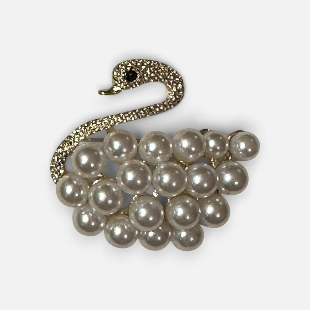 Jakris vintage-inspired swan brooch featuring a textured gold-tone neck and a body made of lustrous white pearls.