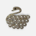Jakris vintage-inspired swan brooch featuring a textured gold-tone neck and a body made of lustrous white pearls.