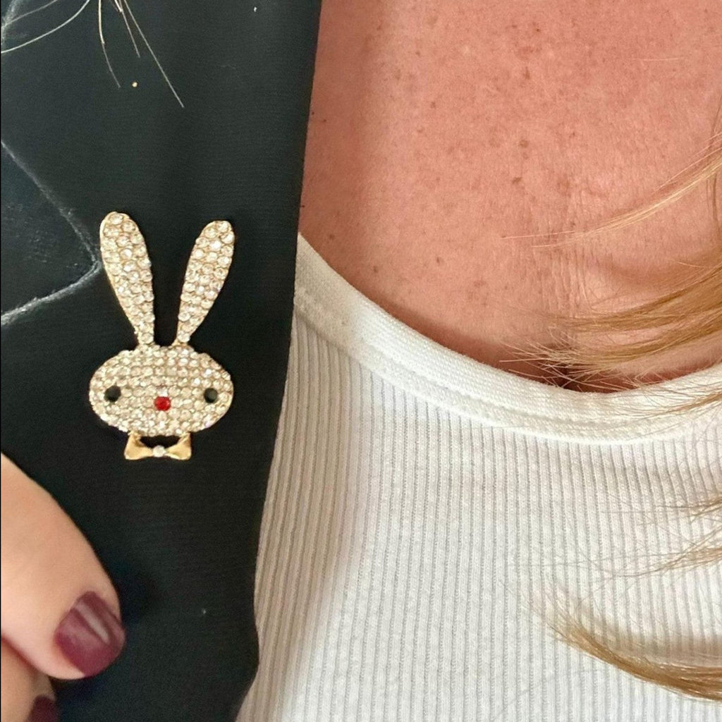 Jakris marka, altın tonlu metal ve kristal taşlarla süslü, siyah ceket üzerinde sergilenen tavşan figürlü broş