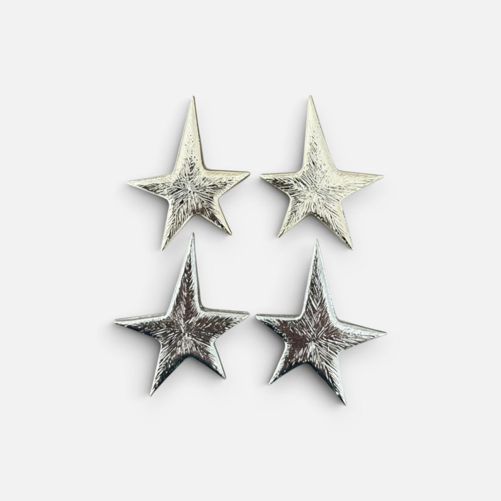 Jakris silver star-shaped earrings with a textured metallic finish displayed on a plain white background.