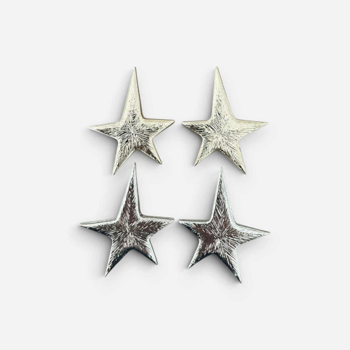 Jakris silver star-shaped earrings with a textured metallic finish displayed on a plain white background.