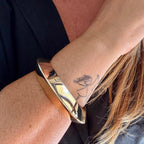 Jakris thick geometric gold-plated cuff bracelet with a hinged clasp worn on a woman's wrist