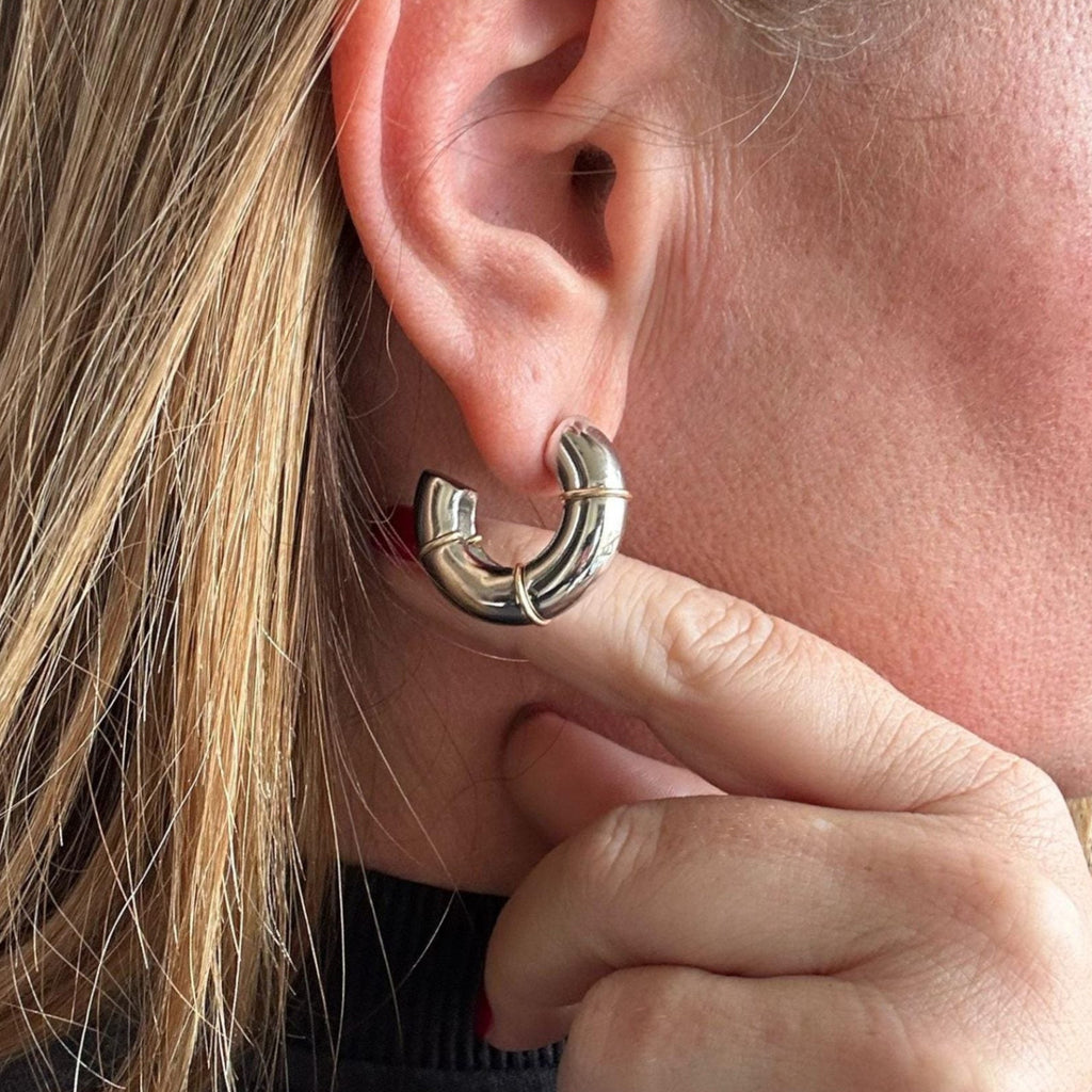 Jakris thick silver hoop earring with gold stripe detail in a modern bamboo style worn on an earlobe