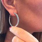 Jakris thick silver hoop earring worn on a woman's ear, showcasing a timeless and classic polished design.