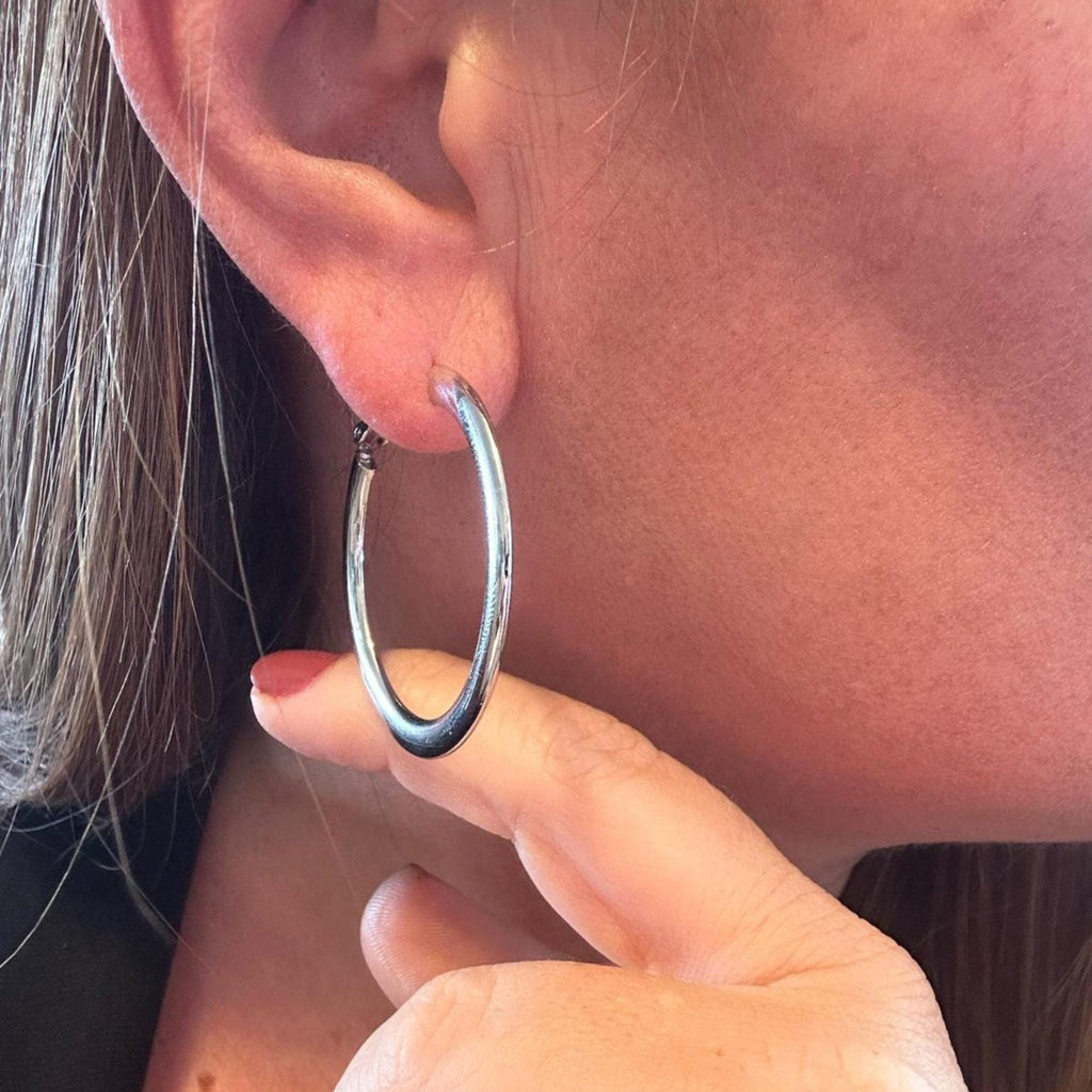 Jakris thick silver hoop earring worn on a woman's ear, showcasing a timeless and classic design.