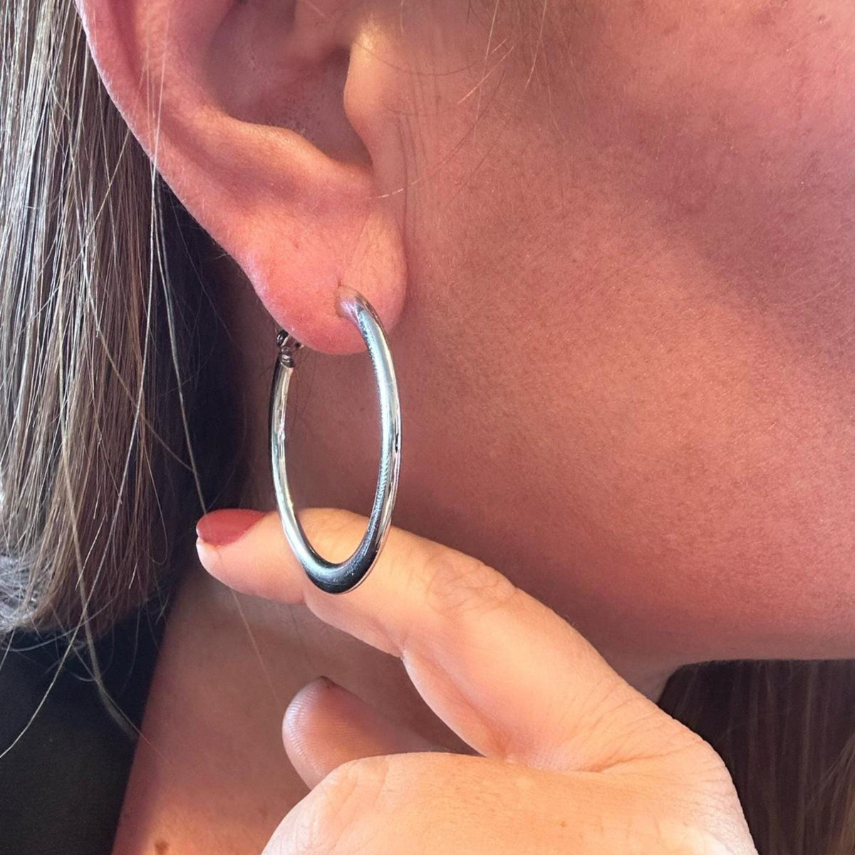 Jakris thick silver hoop earring worn on a woman's ear, showcasing a timeless and classic design.