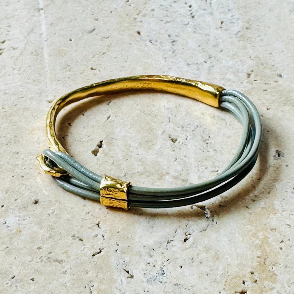 Jakris thin leather bracelet featuring a textured gold-plated bronze cuff and grey leather cords.