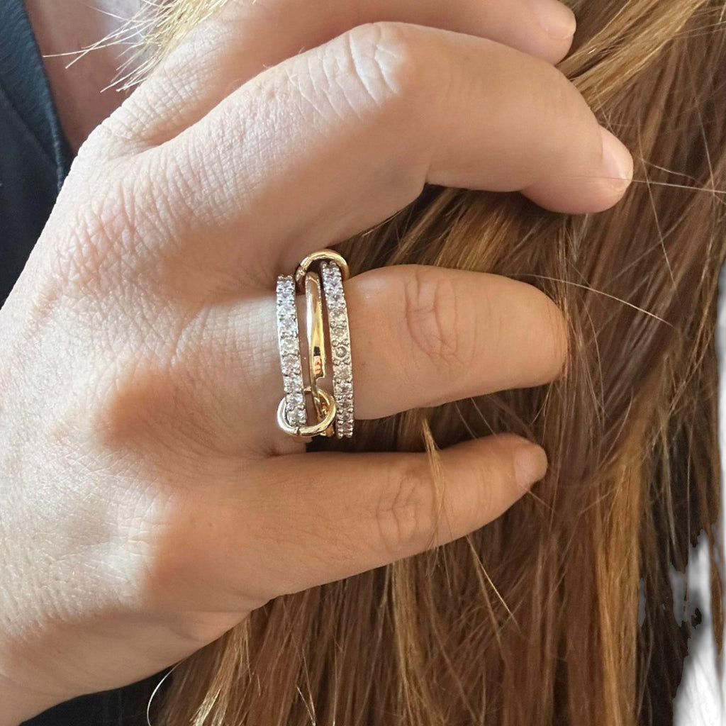 Jakris three-band ring featuring mixed gold and silver tones with sparkling zircon stones worn on a woman's finger.