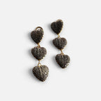 Jakris gold-tone drop earrings featuring three textured dark navy heart charms on a white fabric background.