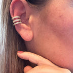 Jakris gold-tone triple row zircon ear cuff worn on the cartilage, featuring a sparkling adjustable clip-on design.
