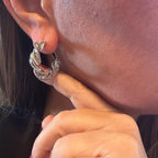 Jakris shiny silver-tone hoop earrings with a twisted textured design worn on an earlobe