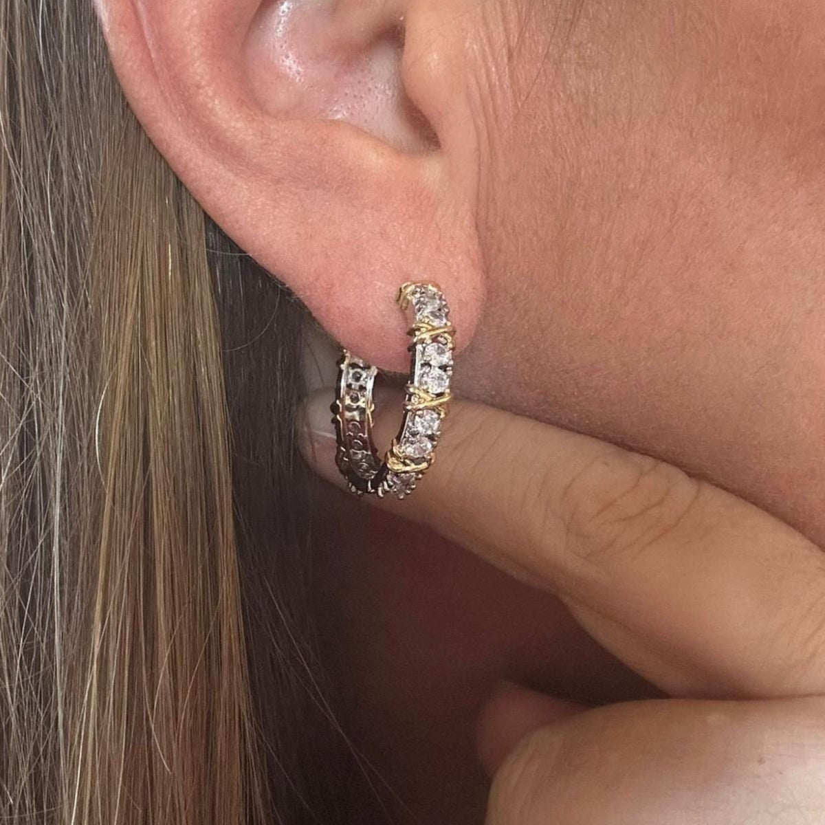 Jakris two-tone gold and silver hoop earring featuring sparkling zircon stones worn on an earlobe