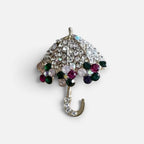 Jakris umbrella brooch featuring sparkling clear, green, and purple crystals on a silver-tone metal setting