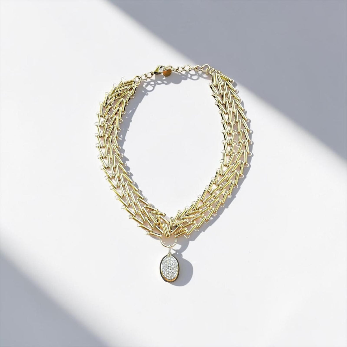 Jakris Zafira gold-plated multi-strand braided chain necklace with a central oval stone-encrusted pendant