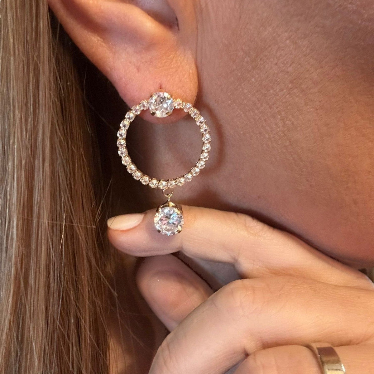 Jakris elegant gold-tone hoop earrings featuring sparkling zircon stones and a dangling central crystal drop