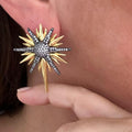 Jakris star-shaped earring featuring gold and silver-toned metal with sparkling zircon stones worn on an earlobe.